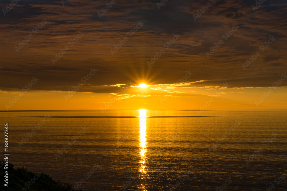 Spectacular sunset over sea with vivd golden colores of water and sky