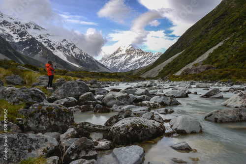 Woman backpacker and photographer taking a photo at Mt Cook in New Zealand