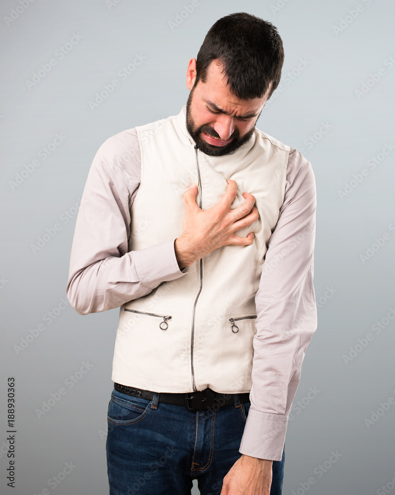 Handsome man with vest with heart pain on grey background