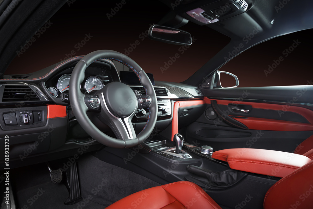 Modern luxury car Interior - steering wheel, shift lever and dashboard. Car interior luxury inside. Steering wheel, dashboard, speedometer, display. Red and black leather cockpit
