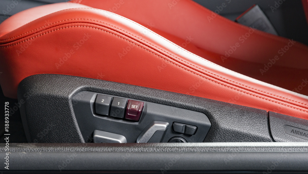 Red leather driver seat with stitching inside luxury car interior, power seat control buttons