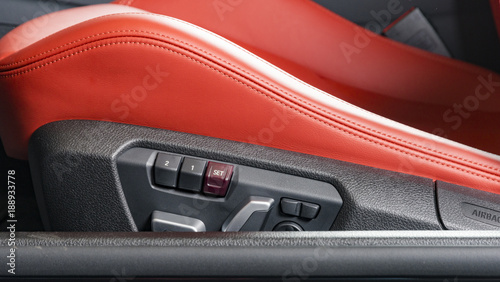 Red leather driver seat with stitching inside luxury car interior, power seat control buttons