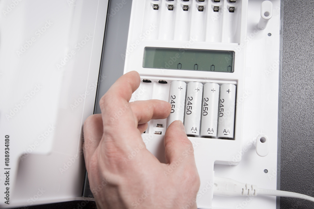 hand of person recharges rechargeable batteries close-up. Battery charging device. Charge accumulators.