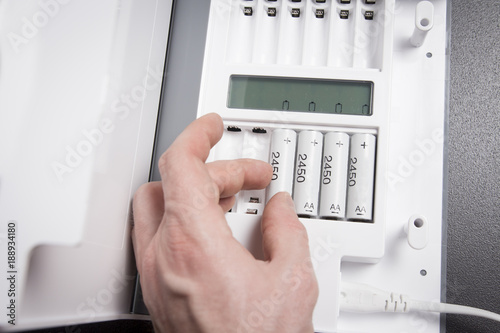 hand of person recharges rechargeable batteries close-up. Battery charging device. Charge accumulators.