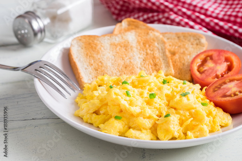 Scrambled egg served with toast and tomato .