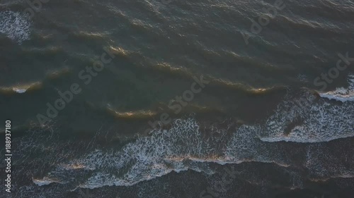 Aerial view of waves crashing on the beach as sunset photo