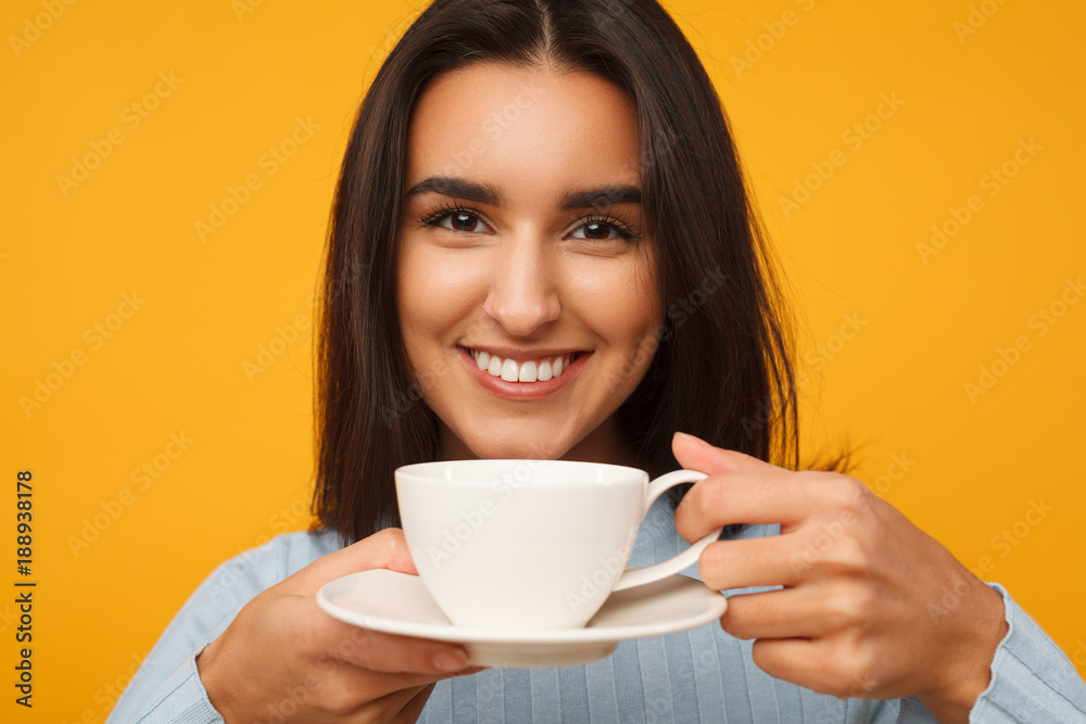 hispanic young woman smiling and holding a cup of coffee hispanic young woman smiling and holding a cup of coffee