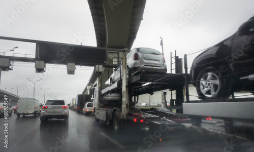 transportation of car on semi-trailer on big highway. Rain on the road