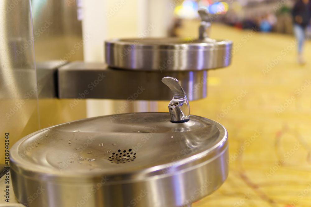 close up of stainless steel public faucet with blurred airport terminal background. close up of stainless steel public faucet with blurred airport terminal background.