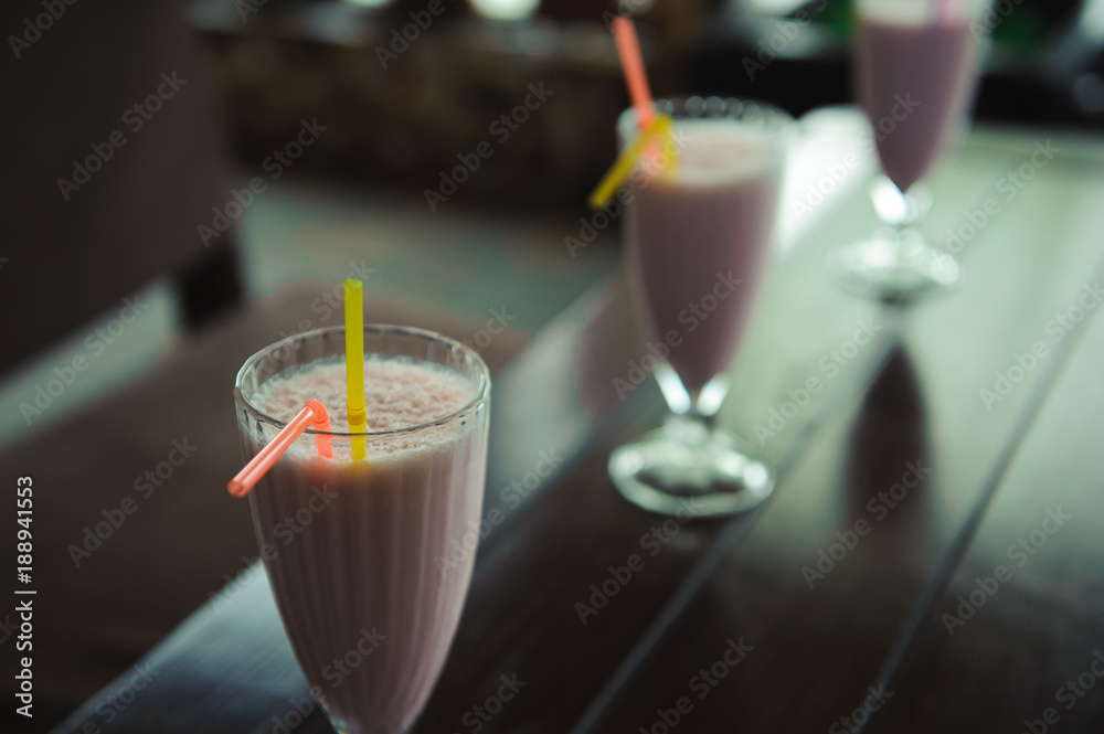 Three jars of pink berry milkshakes with straws on old wooden table Three jars of pink berry milkshakes with straws on old wooden table