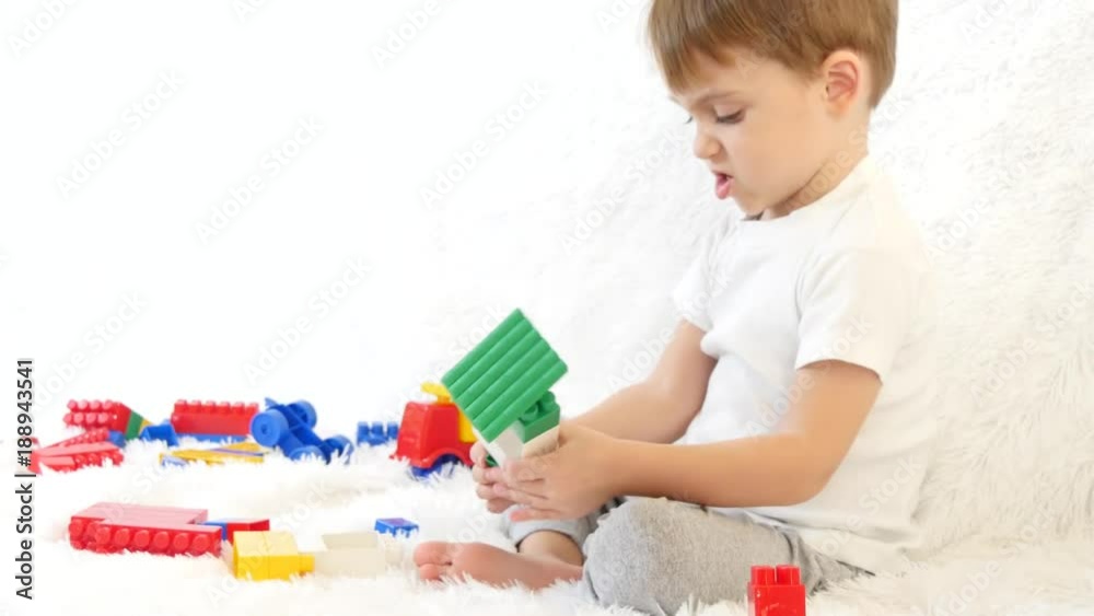 Happy child sitting on couch, playing in colored blocks, sitting on white background. Happy child sitting on couch, playing in colored blocks, sitting on white background.