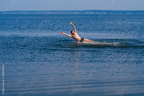 man swims and having fun resting in water with the spray in summer