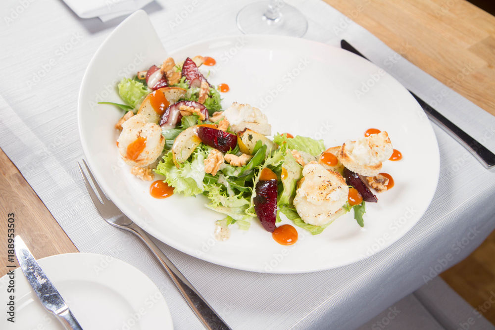 Starter: Mix salads, baked goat cheese, sea-buckthorn jam, caramelized pear with thyme, plum and roast nuts - served in a restaurant Starter: Mix salads, baked goat cheese, sea-buckthorn jam, caramelized pear with thyme, plum and roast nuts - served in a restaurant