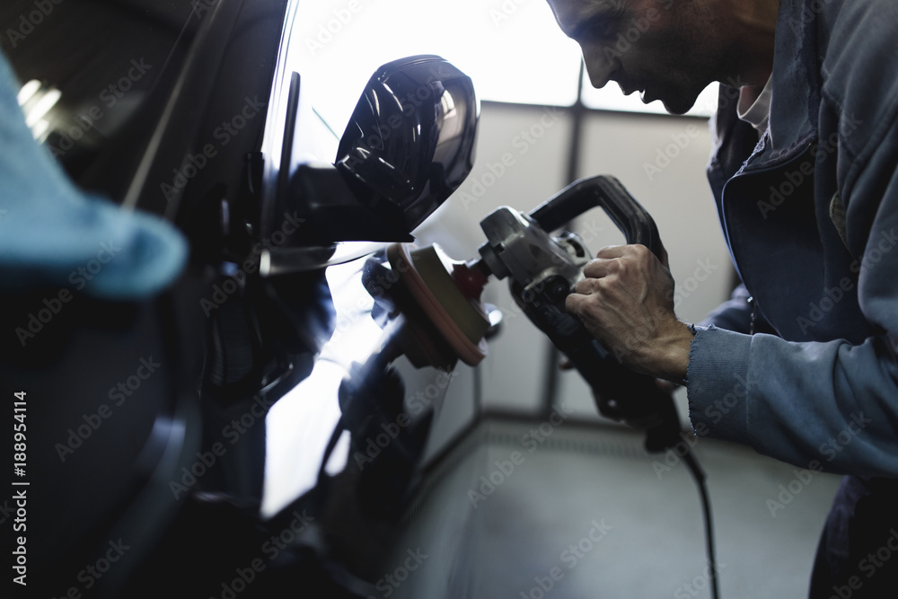 Car detailing - Hands with orbital polisher in auto repair shop. Selective focus. Car detailing - Hands with orbital polisher in auto repair shop. Selective focus.