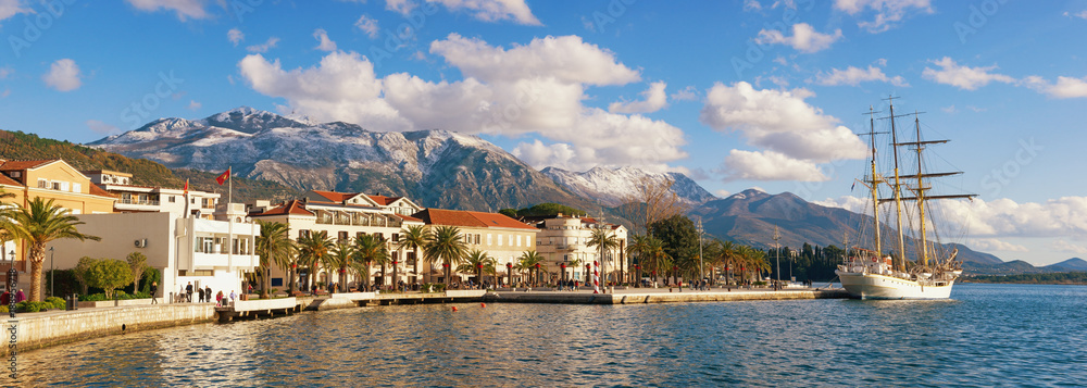 Sunny winter in Mediterranean town. Panoramic view of the embankment of Tivat city and snow-capped Lovcen mountain, Montenegro