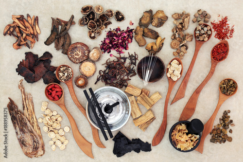 Chinese herbal medicine with traditional herbs, acupuncture needles, moxa sticks used in moxibustion therapy and mortar with pestle on hemp paper background. Top view. photo