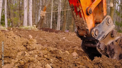Excavator is digging the ground, close up bucket