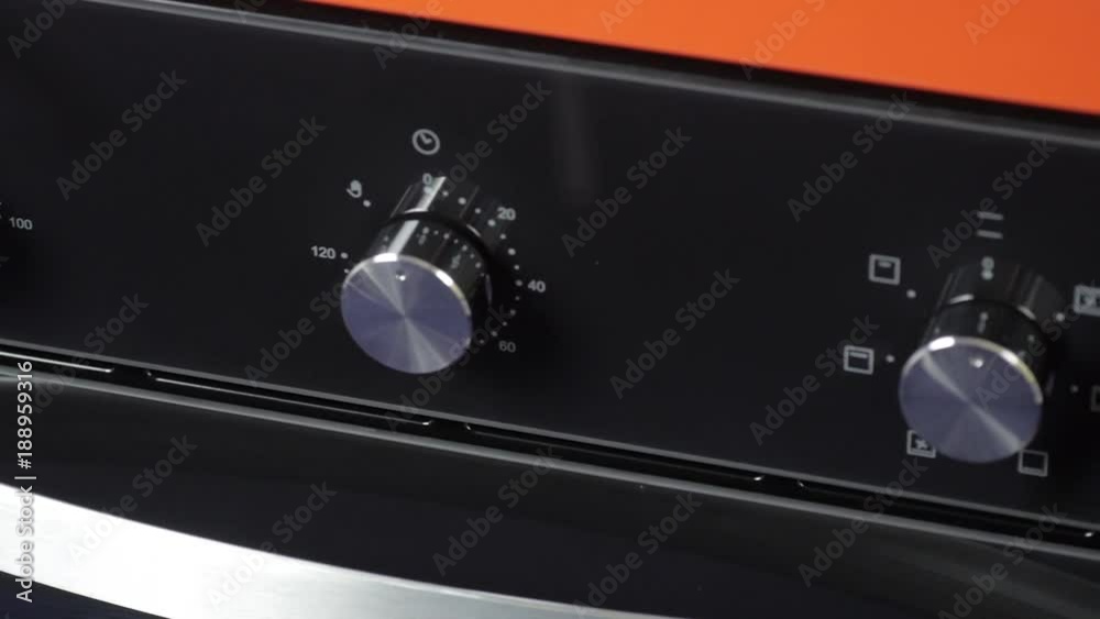 Metallic Toggle Switch of the Cooker Oven. Close-up View. Digital Clock of oven. Front panel of modern black glass oven, red indicators, new shiny buttons. Modern design in details. Metallic Toggle Switch of the Cooker Oven. Close-up View. Digital Clock of oven. Front panel of modern black glass oven, red indicators, new shiny buttons. Modern design in details.