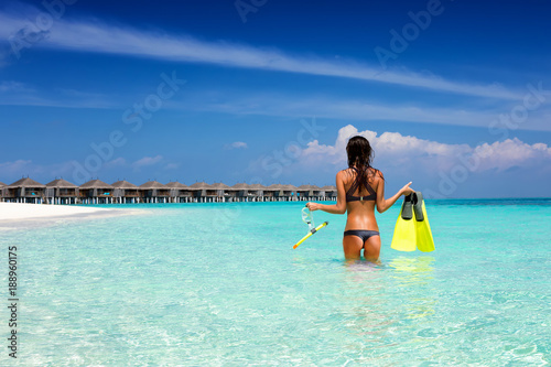 Attraktive Frau im Bikini steht mit Schnorchelausrüstung im tropischen Wasser der Malediven