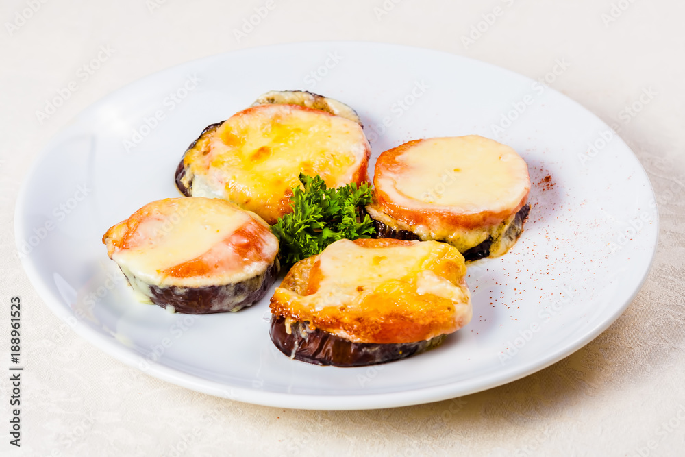 Eggplants baked with tomato and cheese on white plate