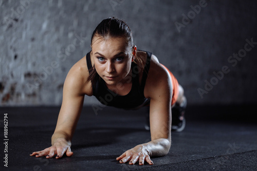 young beautiful woman in sportswear doing plank while trainnig at cross fit gym photo