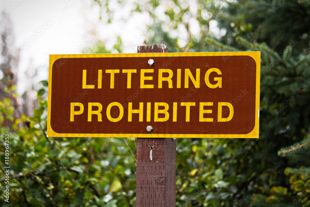 A Littering Prohibited sign with trees in the background