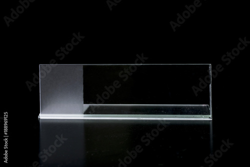 Horizontal standing glass microscope slide, reflecting on a black surface