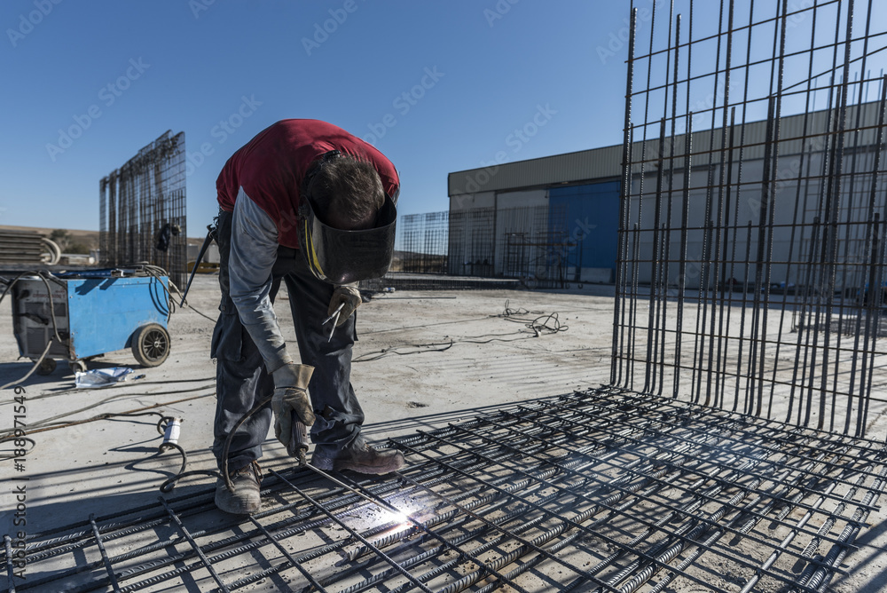 Man makes rebar welds on internal structures that will go inside the cement Man makes rebar welds on internal structures that will go inside the cement