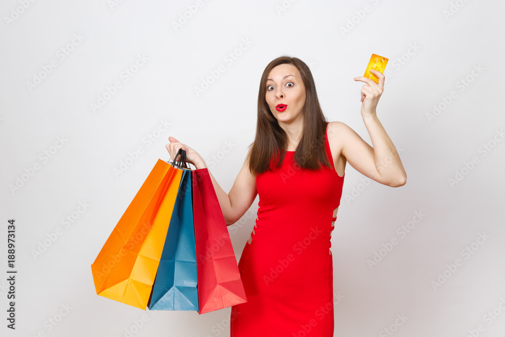 Attractive glamour fashionable young brown-hair woman in red dress holding credit card, multi colored packets with purchases after shopping isolated on white background. Copy space for advertisement. Attractive glamour fashionable young brown-hair woman in red dress holding credit card, multi colored packets with purchases after shopping isolated on white background. Copy space for advertisement.