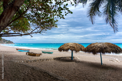 empty tropical beach with straw beach umbrellas