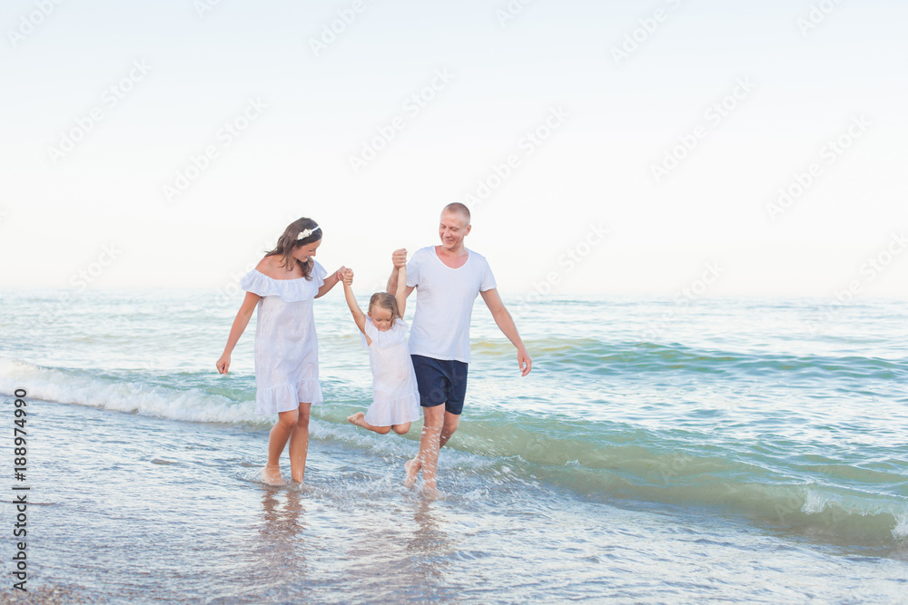 Dad, mom and daughter are walking along the beach.