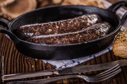 blood sausage in black cast iron baking pot on wooden table 