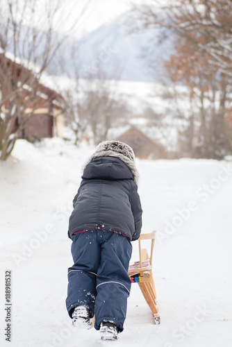 little boy pushing sligh in the snow  photo