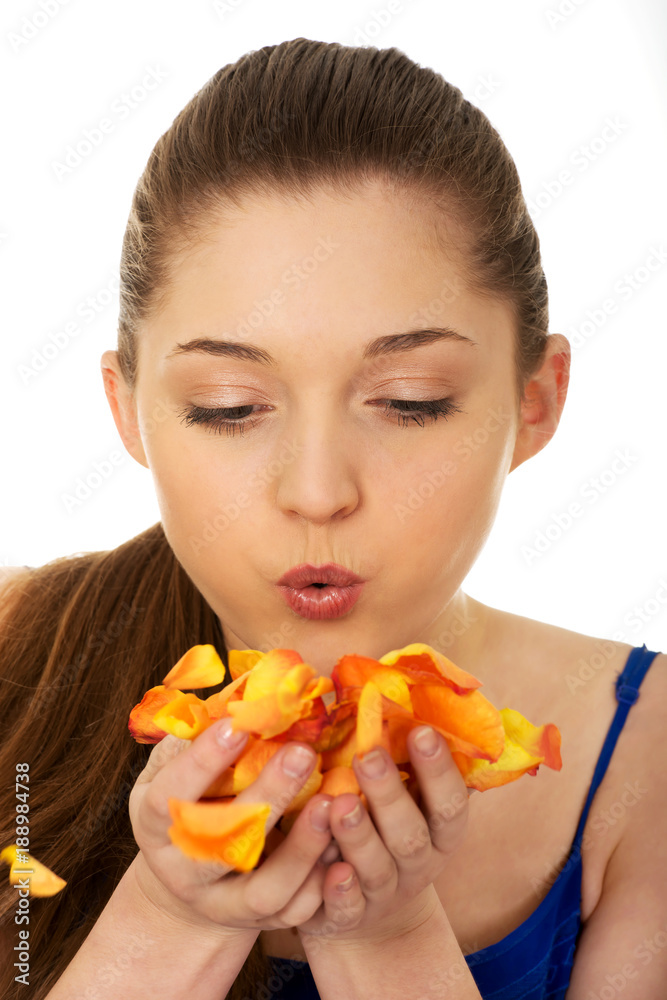Young woman blowing rose petals. Young woman blowing rose petals.