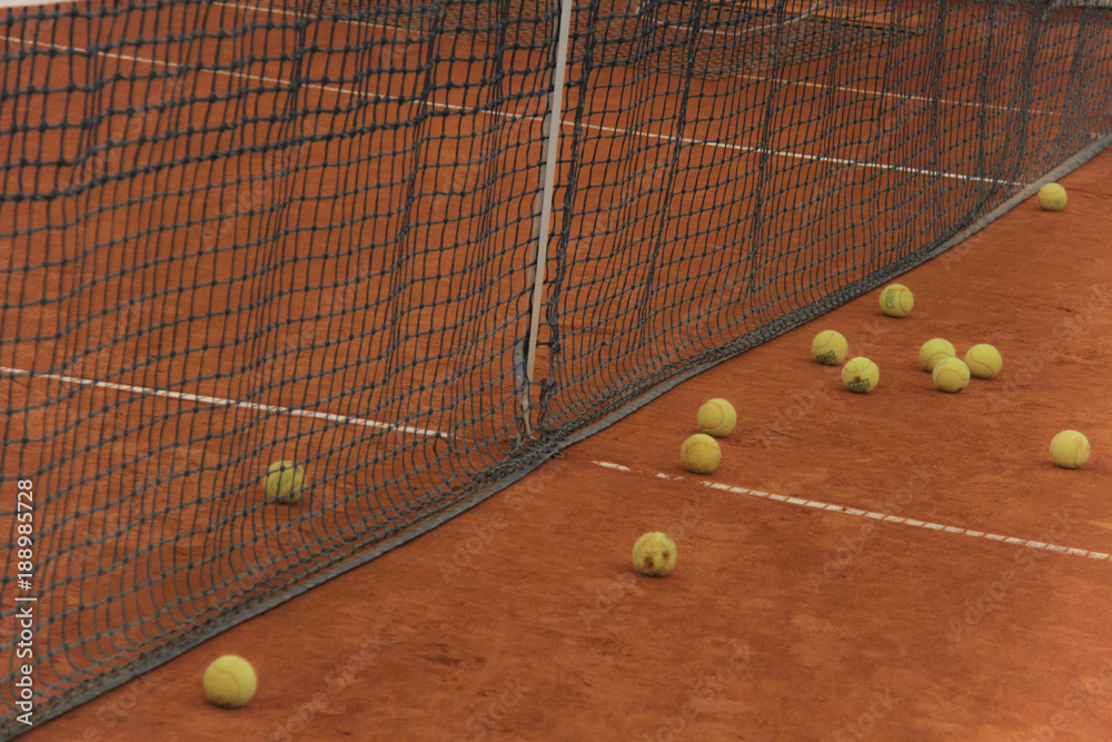 Tennis balls on red court with gray net