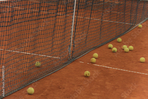 Tennis balls on red court with gray net