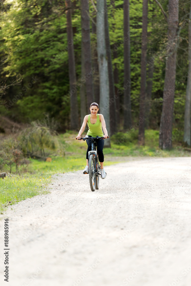 Fototapeta premium The girl rides a bicycle in the park.