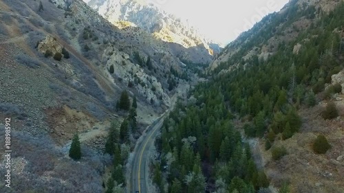 High angle arerial view of a deep canyon road and a car driving down the road photo