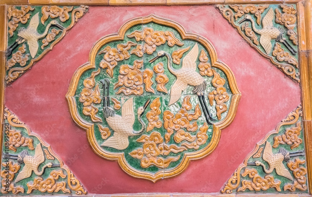 Carved crane and flowers on the red wall of Forbidden City
