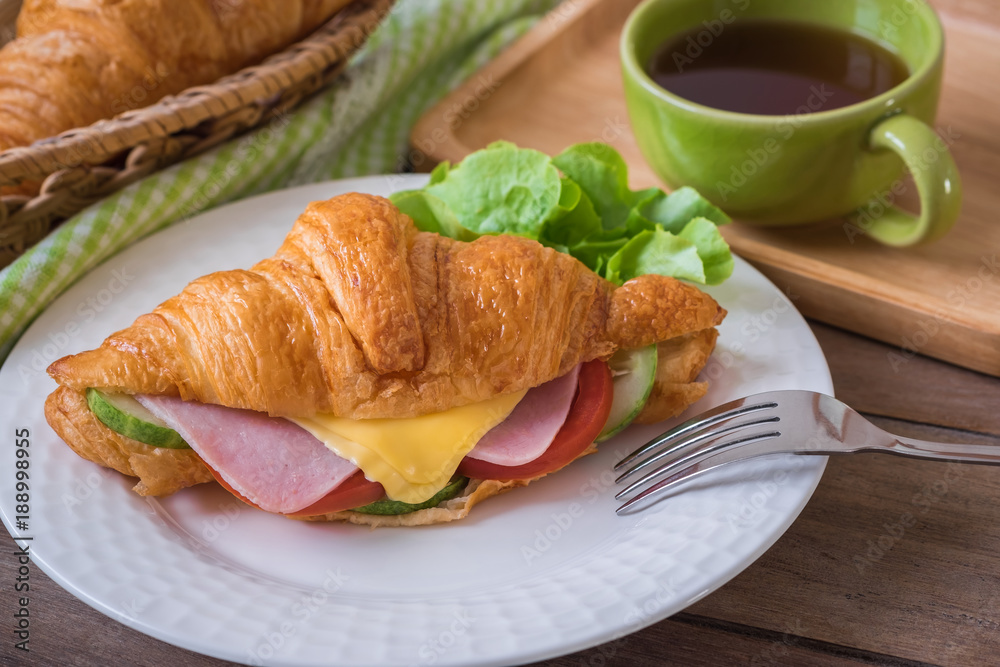 Croissant with ham, cheese on white plate and coffee cup. Croissant with ham, cheese on white plate and coffee cup.