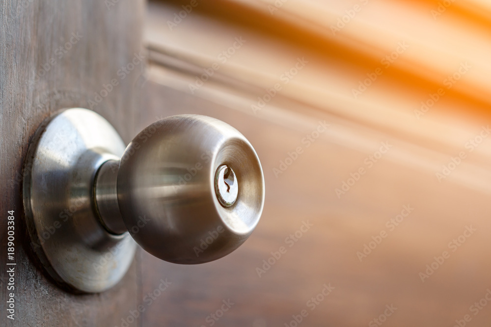 stainless door knob and keyhole on old wooden door with sunlight effect, shallow depth of field - obrazy, fototapety, plakaty 