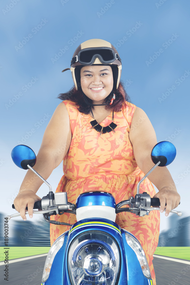 Fat woman riding a scooter on the road Stock Photo | Adobe Stock