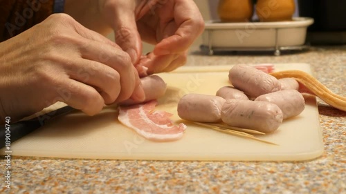 Woman using sharp knife, preparing to make sausages with bacon. pigs in Blankets photo