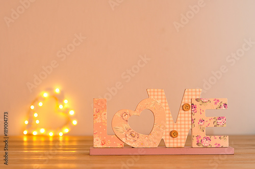 The word love in pink with an out of focus light heart shape