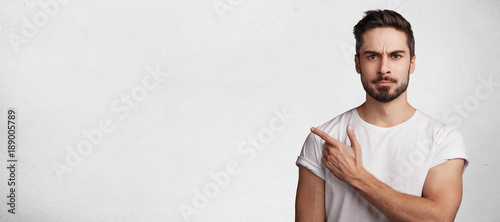 Foto Horizontal shot of attractive brunet male dressed casually, has very strict seri