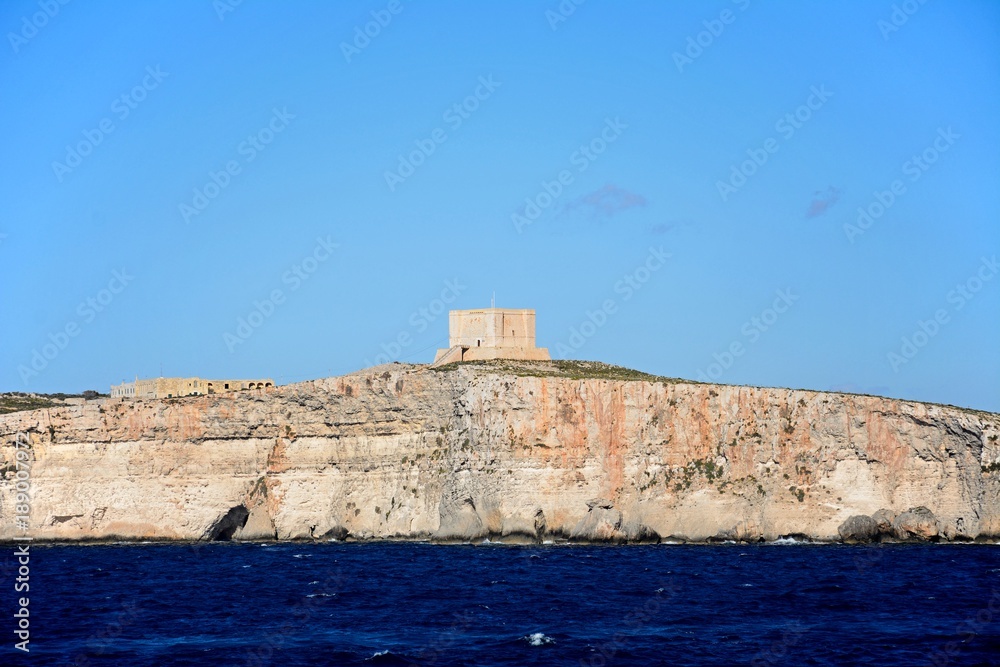 View of the buildings on the clifftops at Comino, Malta. View of the buildings on the clifftops at Comino, Malta.