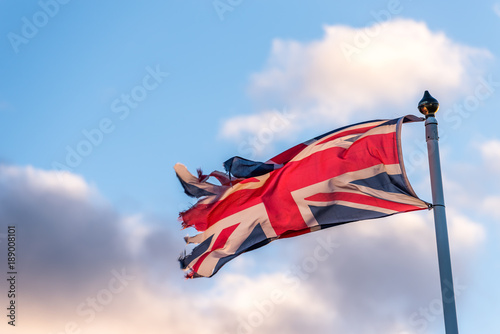 British Flag with torn edges waving over cloudy sky photo