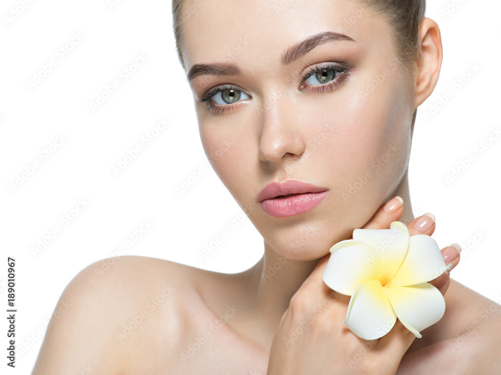 Beautiful face of young woman with flower near face Beautiful face of young woman with flower near face