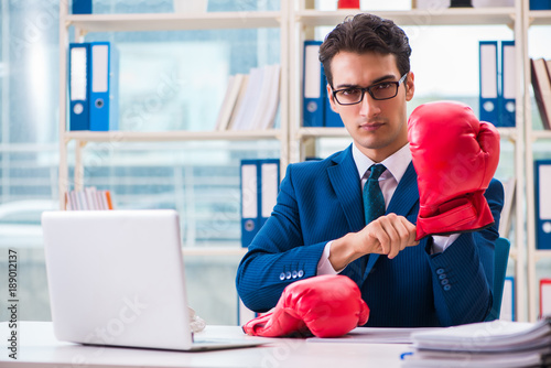 Businessman with boxing gloves angry in office