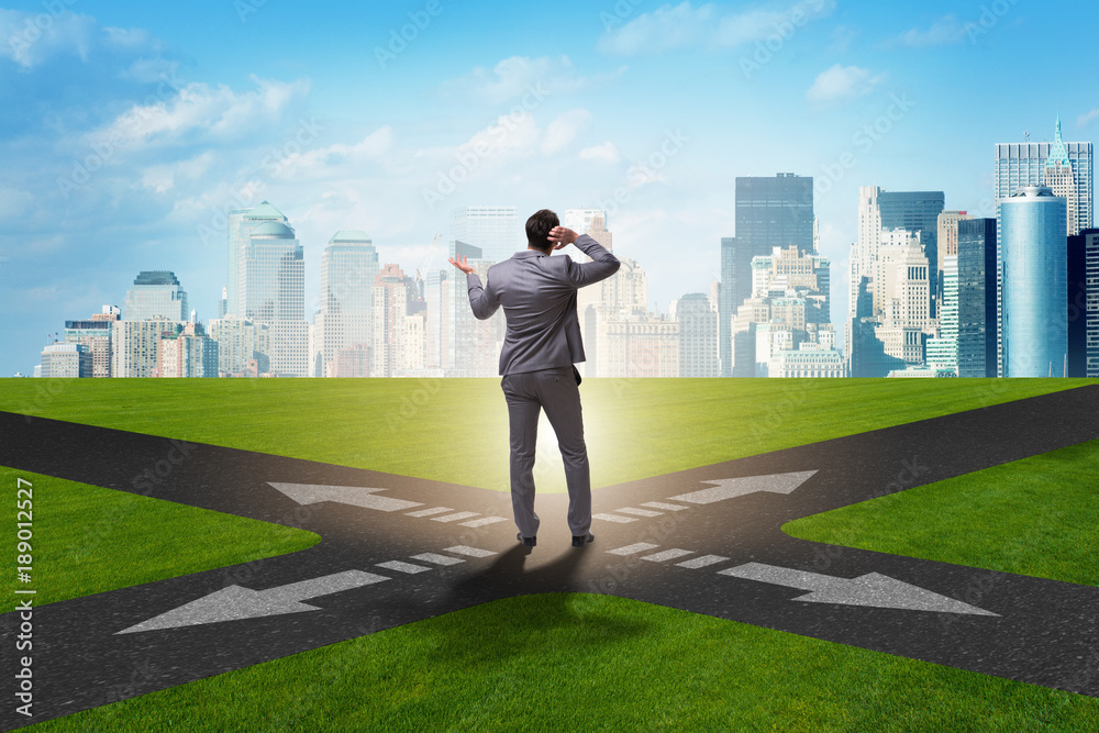 Young businessman at crossroads in uncertainty concept Young businessman at crossroads in uncertainty concept